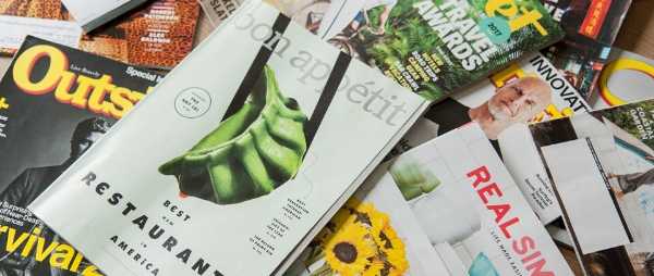 A variety of magazines are pictured. They are laying haphazardly in a pile.