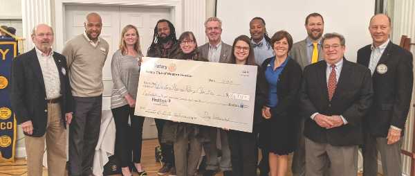 A group of people stand in a line. they are holding an over-sized check.