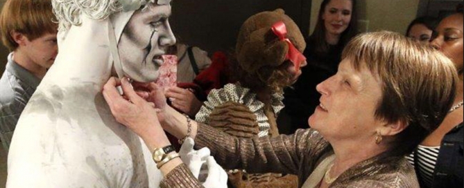 A woman reaches to touch the face of an actor in costume