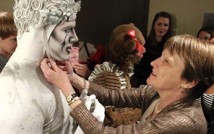 A woman reaches to touch the face of an actor in costume
