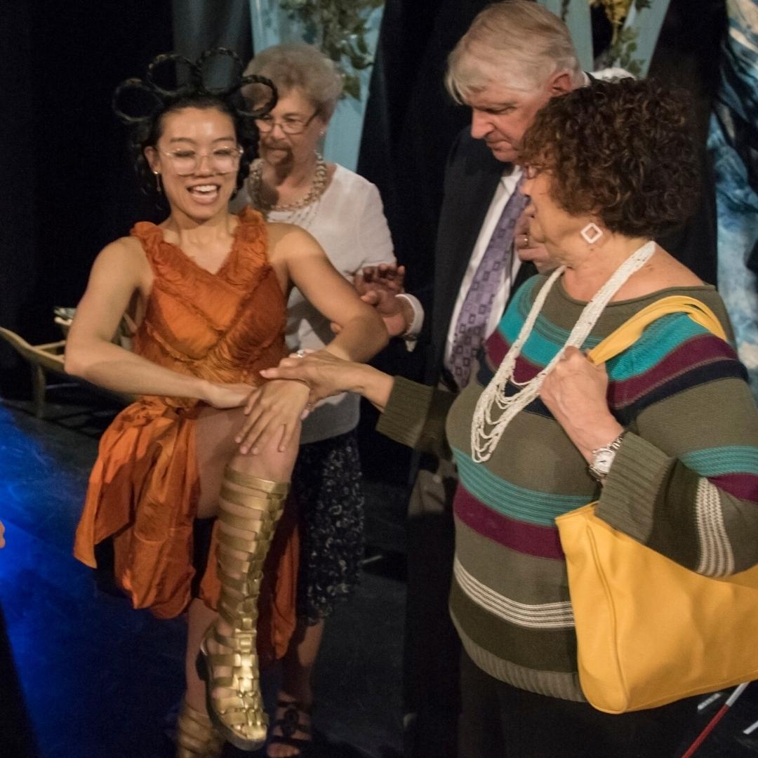 Live Audio Describer attendee touching an actor's leg during the tactile tour