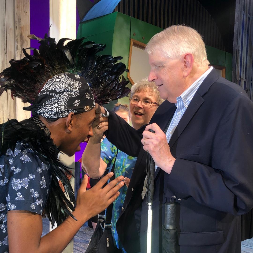 Live Audio Describer touching an actor's costume during the tactile tour