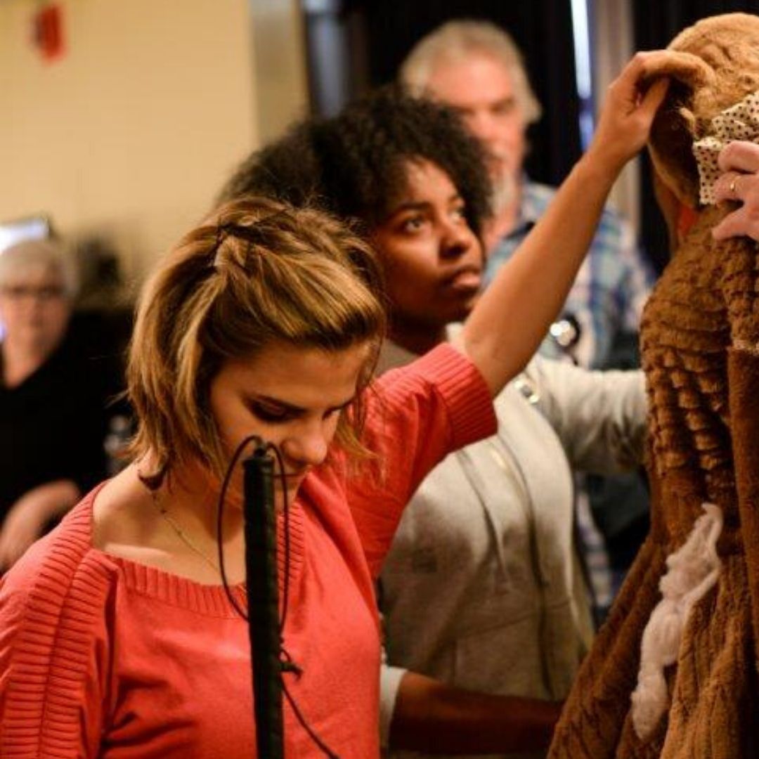 Live Audio Describer attendee touching an actor's fact during the tactile tour